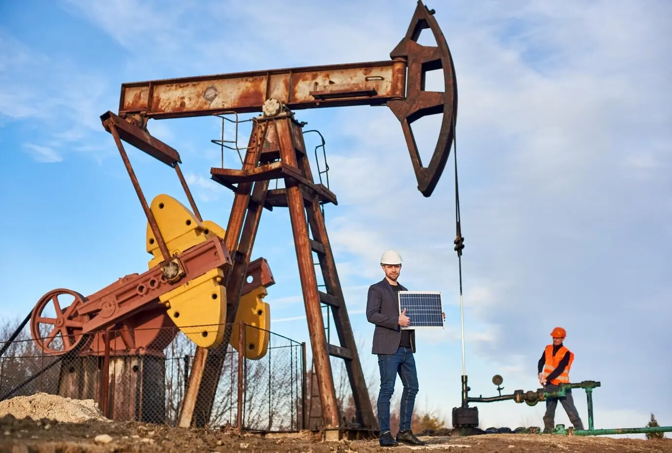 Pump jack in operation with engineers in an oil field on a sunny day